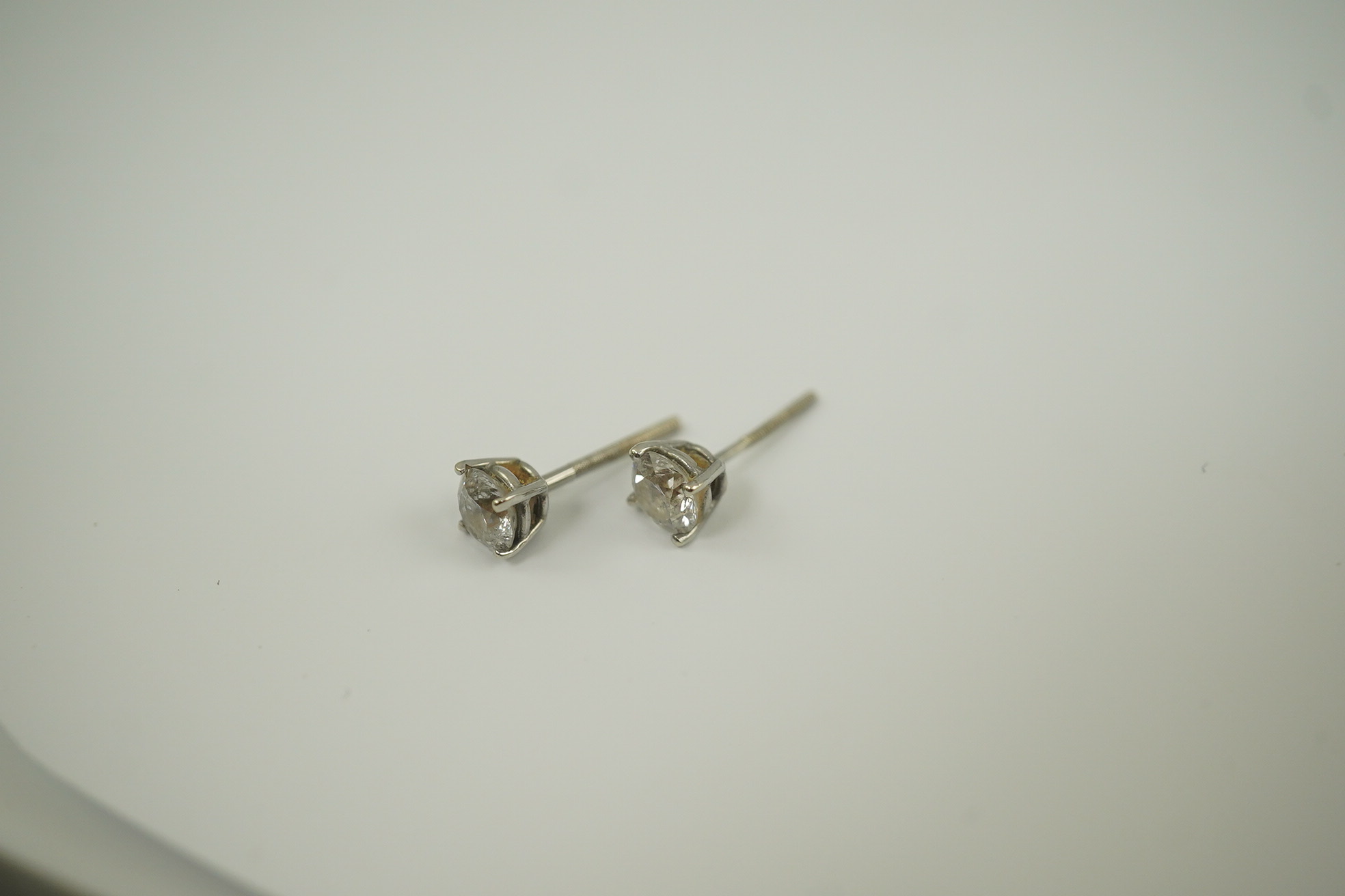 A pair of 14k white gold and solitaire diamond set ear studs